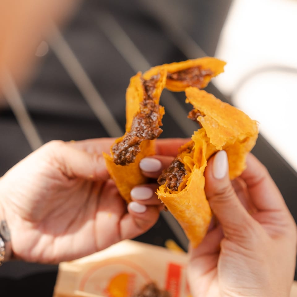 Hands pull apart a golden, flaky patty to reveal its savory filling.