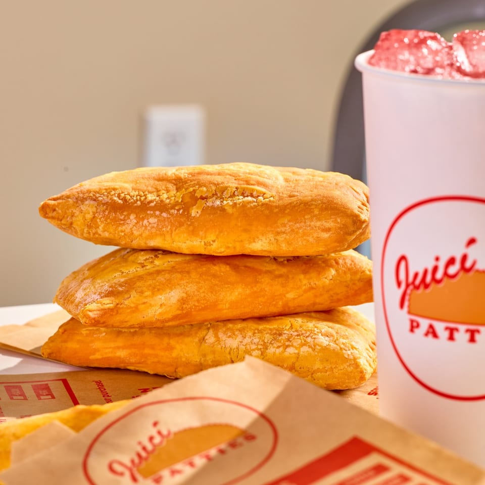 Golden Juici Patties stacked beside a branded cup with a red iced drink.