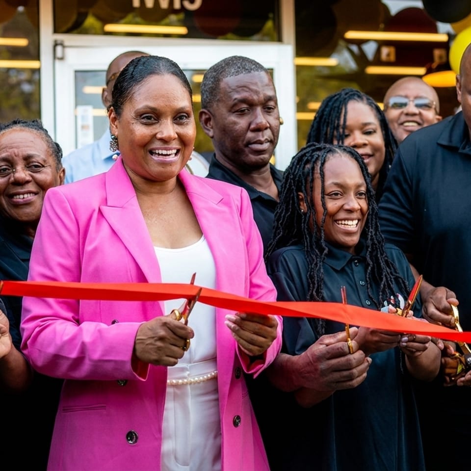 Smiling people cutting a red ribbon for the Bakizas restaurant grand opening.