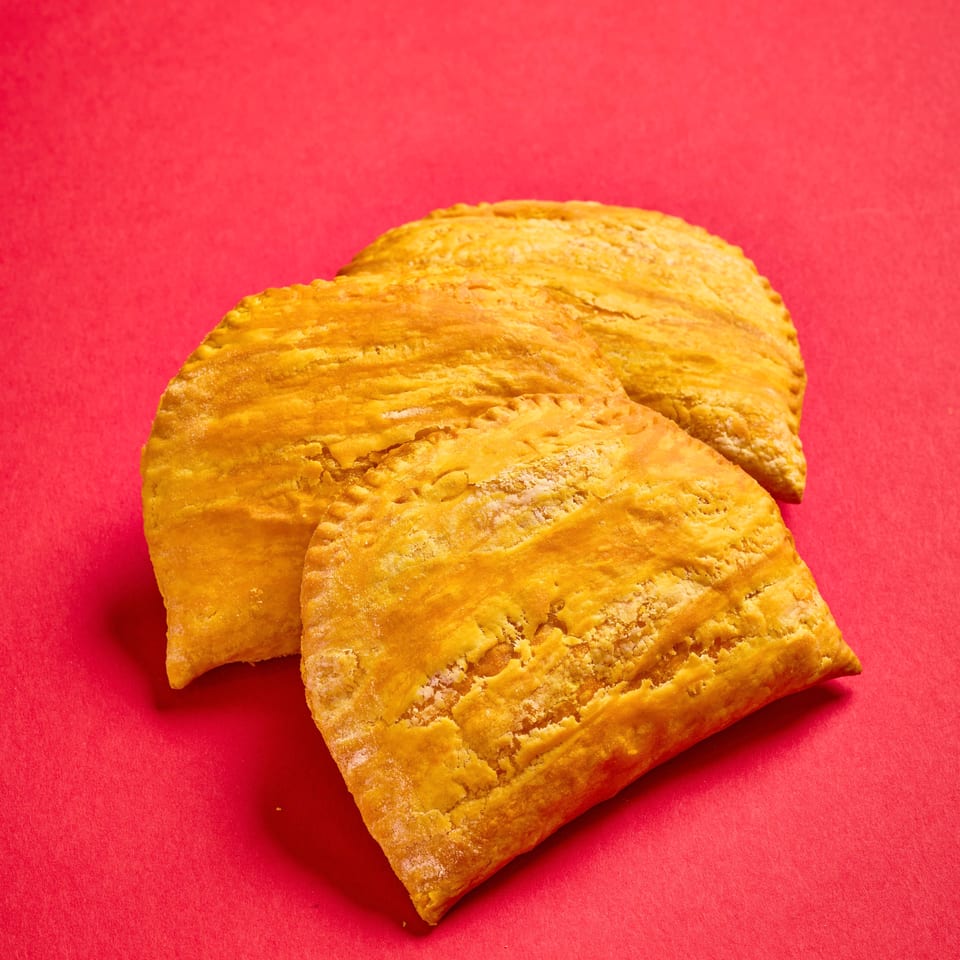 Three golden, flaky rectangular pastries arranged on a vibrant red surface.
