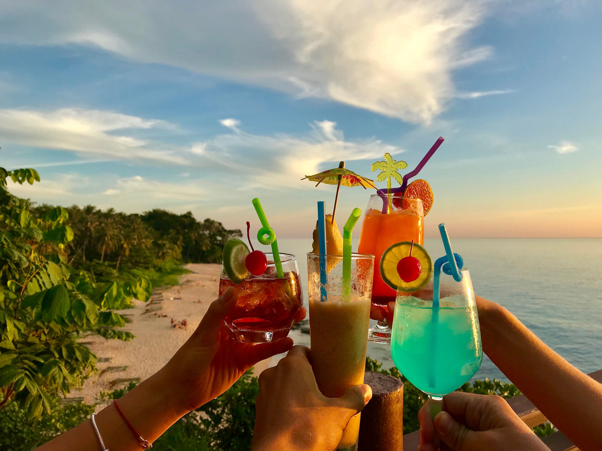 Hands Clinking With Cocktails Glasses Over Beach, Sea And Sky Background, Summer Tropical Vacation Hands Clinking With Cocktails Glasses Over Beautiful Beach, Sea And Sky Background, Summer Vacation On Tropical Resort